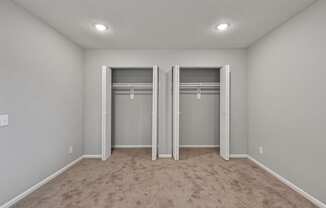 an empty bedroom with two closets and a carpeted floor