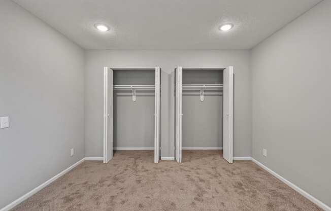 an empty bedroom with two closets and a carpeted floor