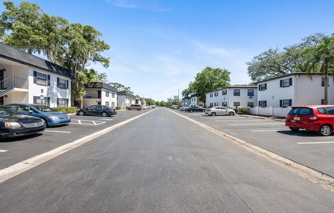 Inviting apartment complex featuring charming two-story buildings with ample parking, surrounded by lush greenery and clear blue skies.