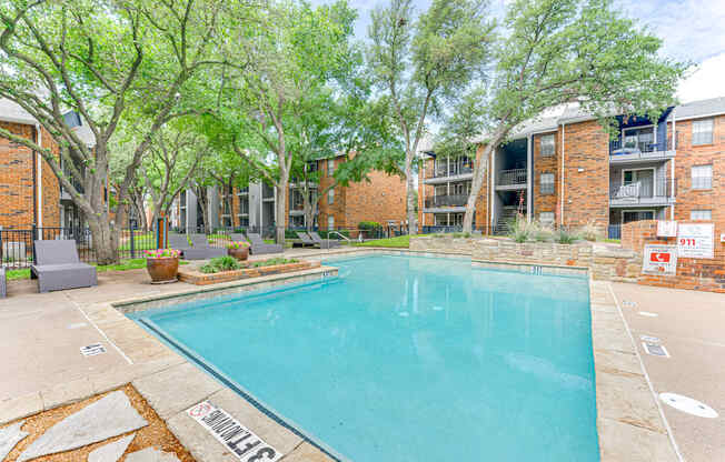 A swimming pool surrounded by trees and apartment buildings.