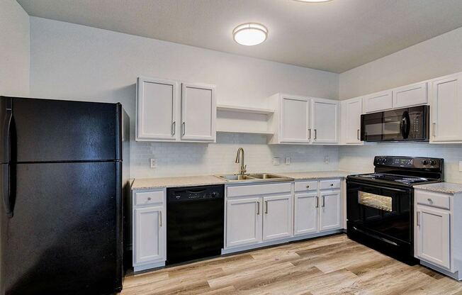 a kitchen with white cabinets and black appliances