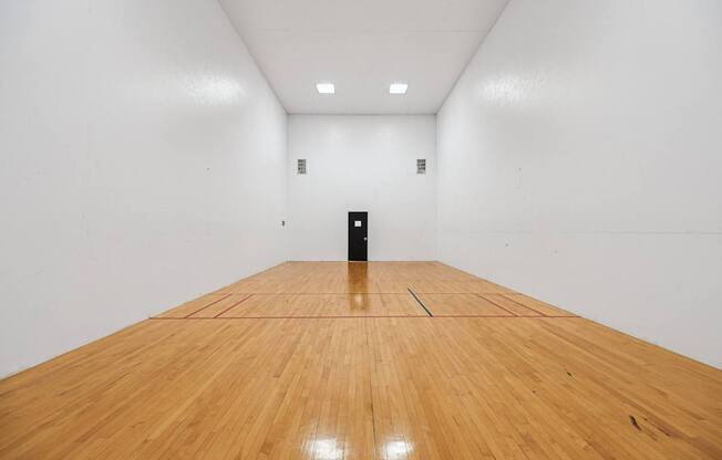 A black object is placed in the middle of a room with wooden flooring.