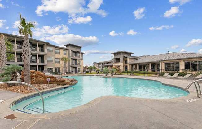 A large swimming pool in front of a building with a palm tree.