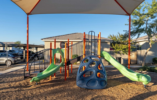 A playground with a green slide and a blue ball-shaped structure.
