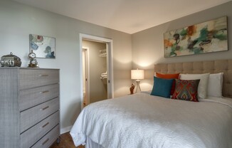 Model bedroom at our apartments for rent in Washington DC, featuring wood grain flooring and a view of the bathroom.