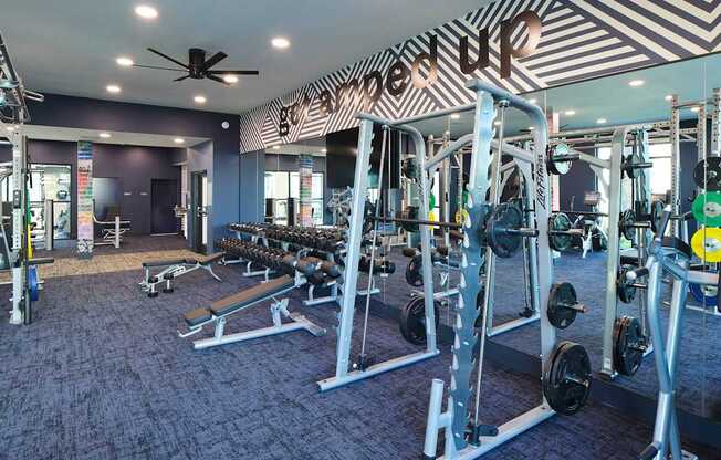 a gym with weights and a ceiling fan