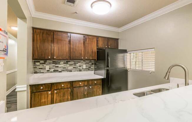A kitchen with a black refrigerator and wooden cabinets.