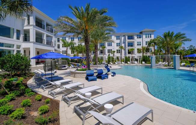 a swimming pool with lounge chairs and umbrellas in front of an apartment building at Altis Grand Lake Willis, Orlando