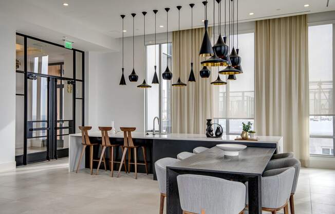 a kitchen and dining area with a long black countertop and black pendant lights