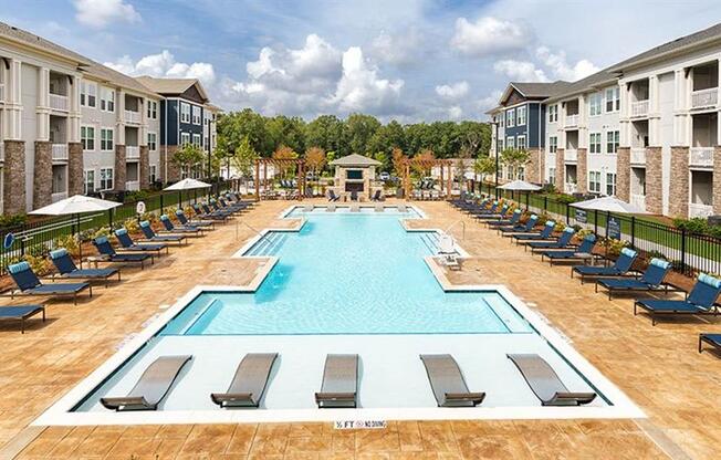 an outdoor pool with lounge chairs and umbrellas at an apartment building at Promenade at Newnan Crossing, Georgia