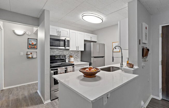 A kitchen with a white countertop and a bowl of fruit on it.