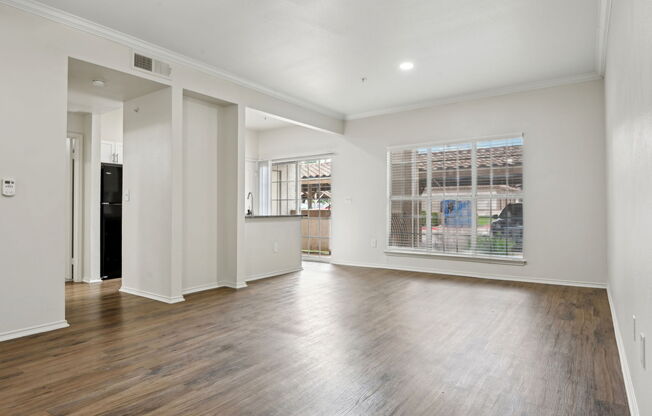 A spacious room with wooden floors and white walls.