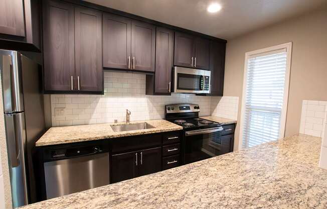 A kitchen with granite countertops and black cabinets.