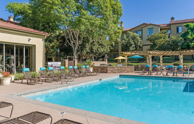 A large swimming pool surrounded by lounge chairs and trees.