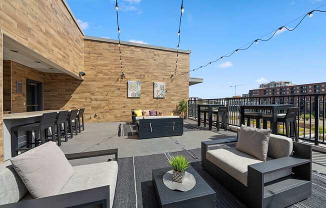 a roof deck with couches tables and chairs and a bar