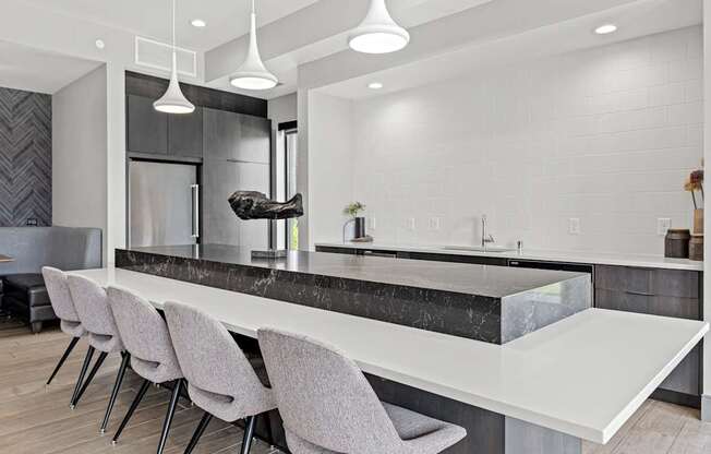 A modern kitchen with a marble countertop and grey chairs.