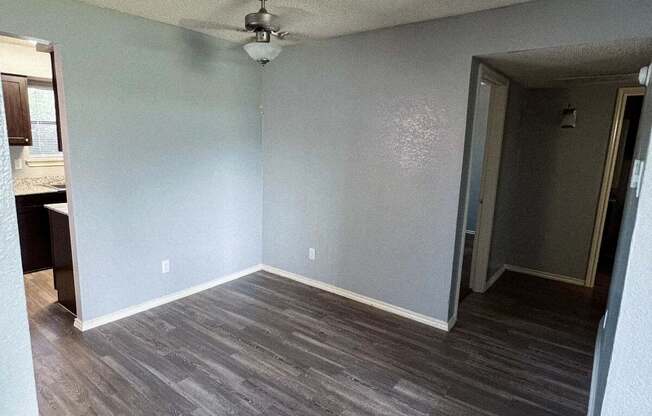 an empty living room with wood floors and a ceiling fan