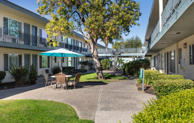 a courtyard with tables and chairs in front of a building