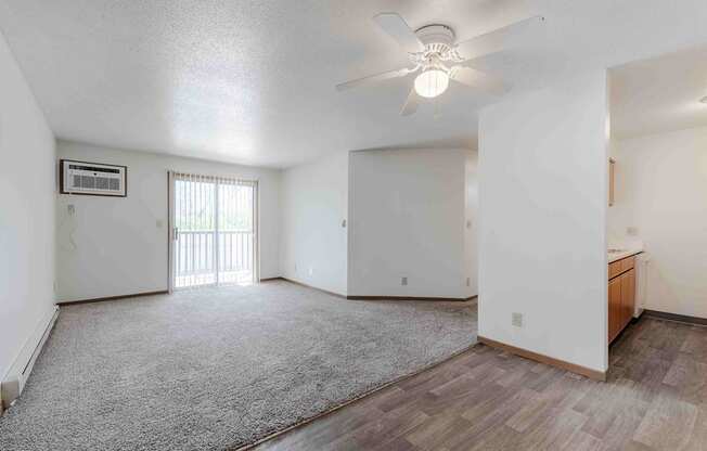 A spacious room with a ceiling fan and a window with blinds.
