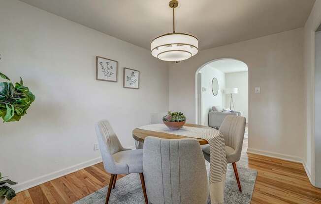 A dining room with a round table and grey chairs.