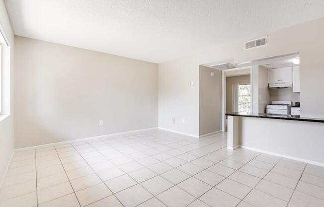 an empty living room and kitchen with a tiled floor