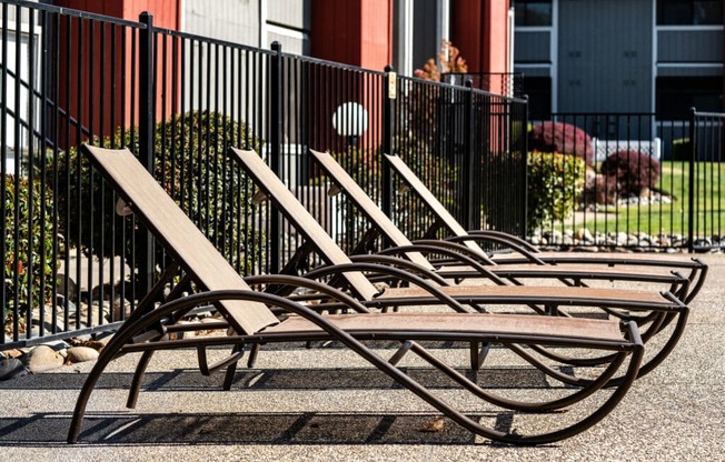 A row of sun loungers are lined up on a paved area.