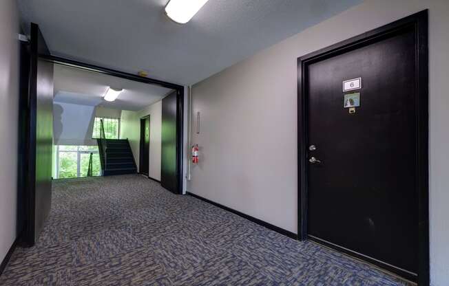 an empty hallway with a black door and a staircase at Highland Club apartments, Watervliet, NY 12189