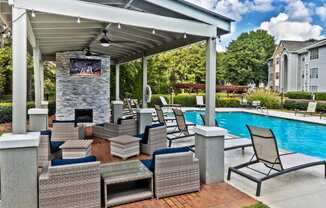 covered pavilion with tv and fire pit next to pool
