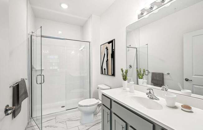 A modern bathroom with a glass shower stall and a white toilet.