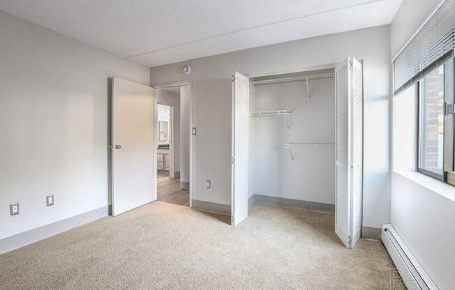 A room with a carpeted floor and a white wall with a door and a window.