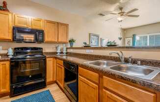 a kitchen with a sink and a stove and a ceiling fan