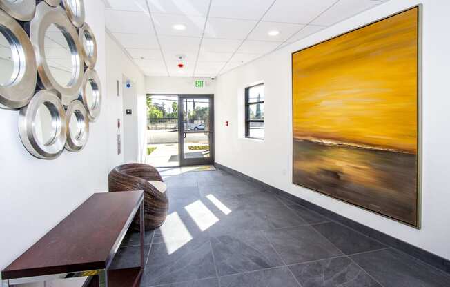 a hallway with paintings on the wall and a table and chairs