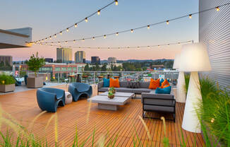 a roof deck with couches and chairs and a city in the background