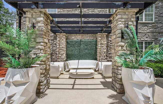 A patio with white chairs and a stone wall.