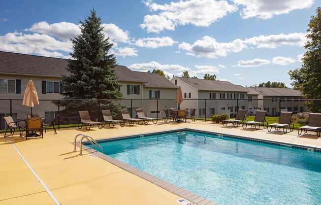 outdoor pool on a sunny day with multiple deck chairs