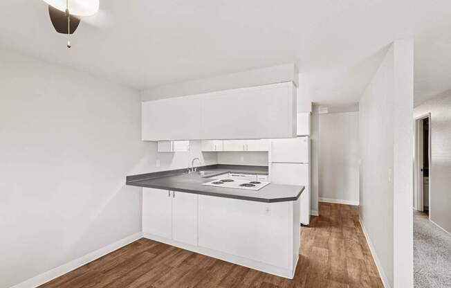 Kitchen A modern kitchen with white cabinets and a wooden floor.