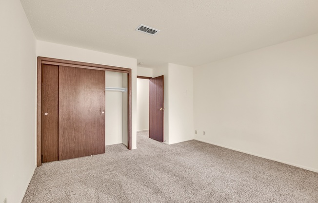 A room with carpeted floor and two doors.