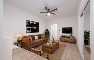 A living room with a brown couch and a ceiling fan at Westmore Manor Apartments, Los Angeles, 90020