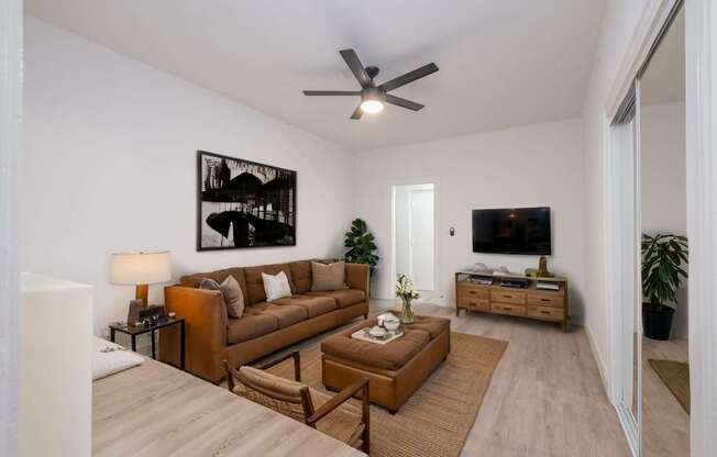 A living room with a brown couch and a ceiling fan at Westmore Manor Apartments, Los Angeles, 90020