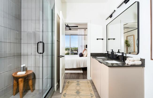 The bathroom features a spacious double vanity with generous storage, a sleek walk-in shower with designer tile, and clean modern finishes throughout.