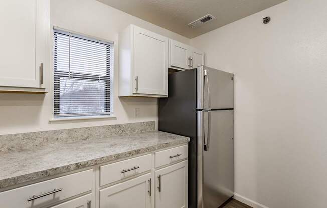 A kitchen with a black refrigerator and white cabinets.