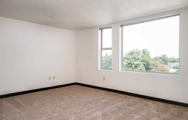 an empty room with two windows and a carpeted floor