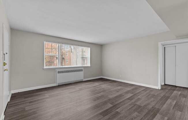 the living room of an apartment with wood flooring and a window