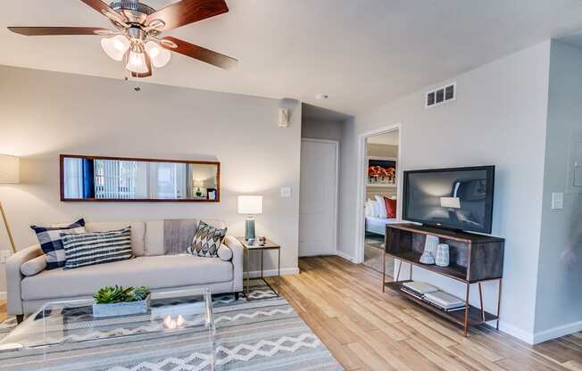 a living room with a ceiling fan and a flat screen tv