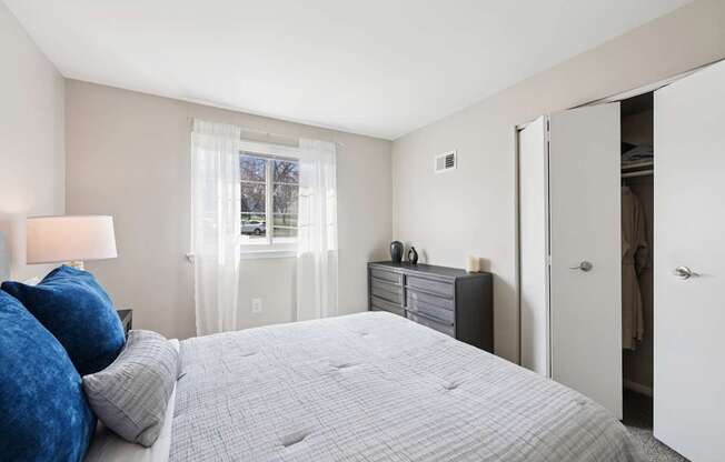 A bedroom with a large bed and a window with curtains.