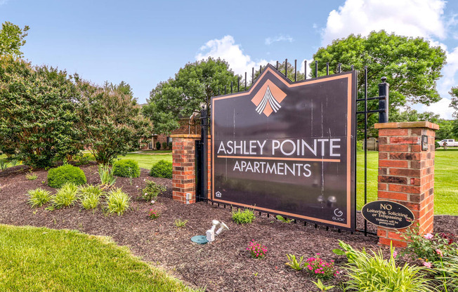 Community entrance at Ashley Pointe Apartments with brick sign and flower beds.