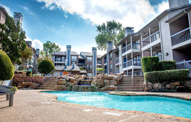 a swimming pool with a waterfall in front of an apartment building