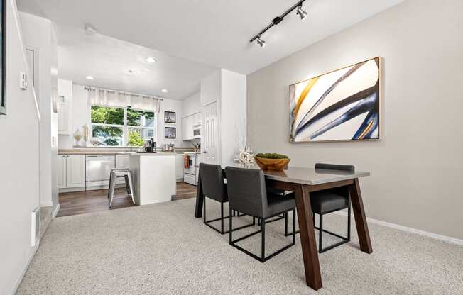 a dining area with a table and chairs and a kitchen in the background