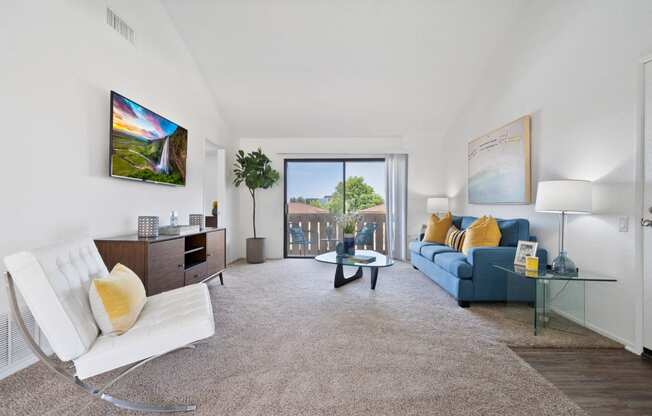 a living room with a blue couch and a white chair and a sliding glass door