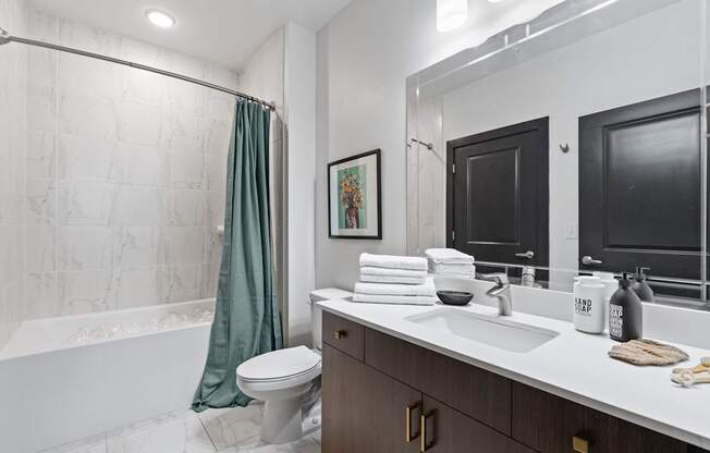 A bathroom with a white tub, sink, and toilet.